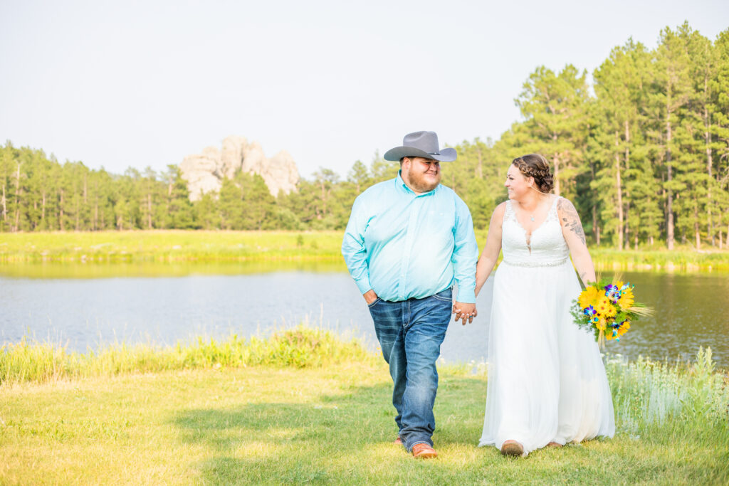 Reception must haves with a bride and groom walking on their wedding day in front of a lake in the Black Hills headed to their reception.